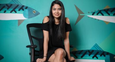 Billionaire Melanie Perkins sitting down in a little black dress