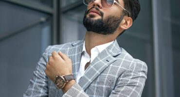 Wealthy man standing outside his office in an expensive suit, watch and sunshades.
