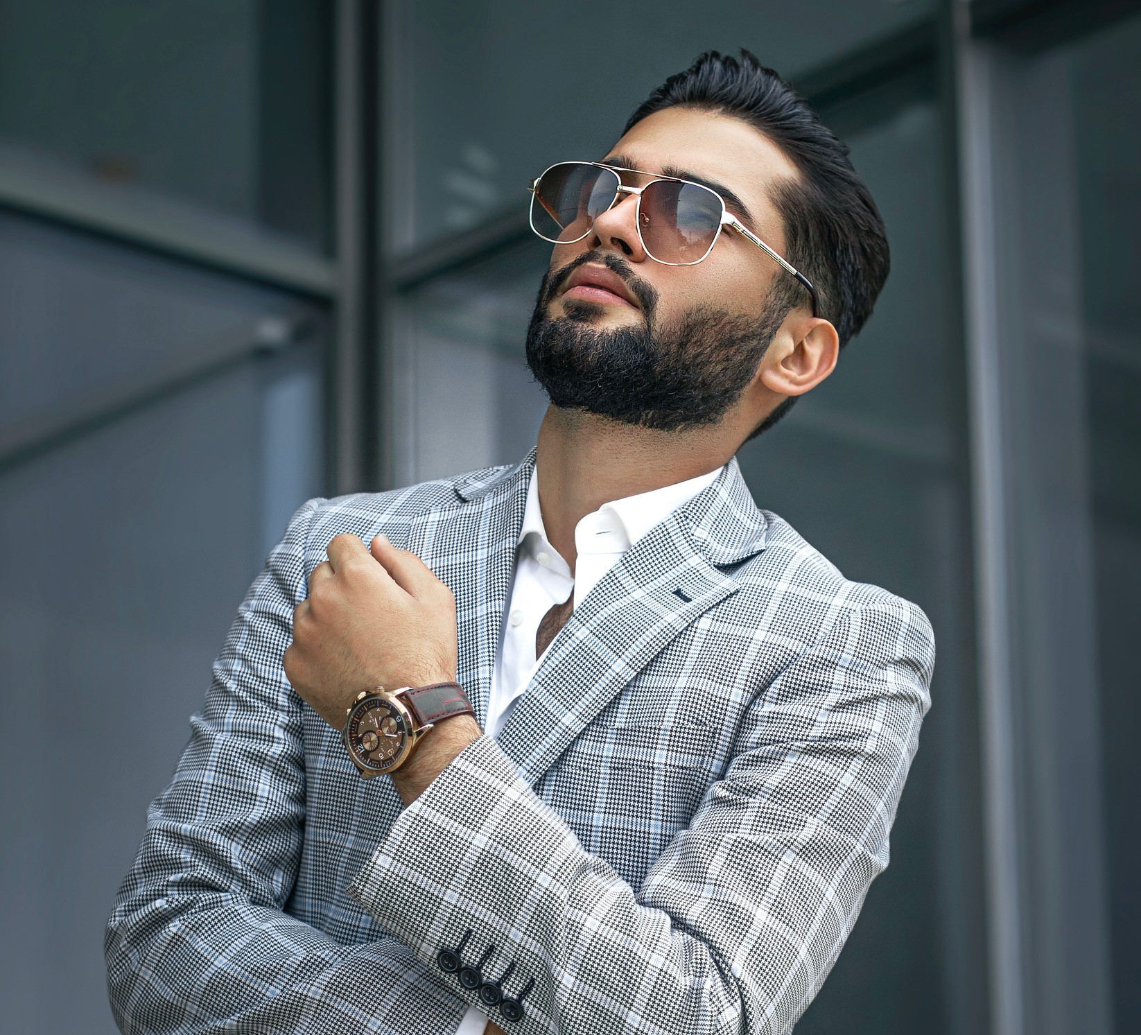 Wealthy man standing outside his office in an expensive suit, watch and sunshades.