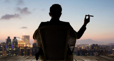 A wealthy Investor relaxing outside his penthouse with a cigar